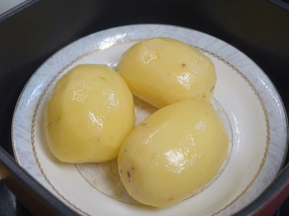 Pommes de terre cuites à la vapeur sur une assiette prêtes à être enduites dhuile.