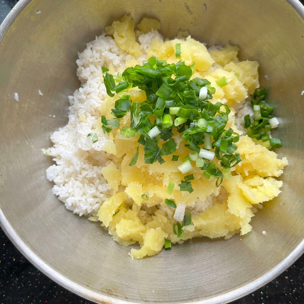 Morceaux de pommes de terre cuites au four et assaisonnements combinés avec du riz cuit dans un bol en métal.