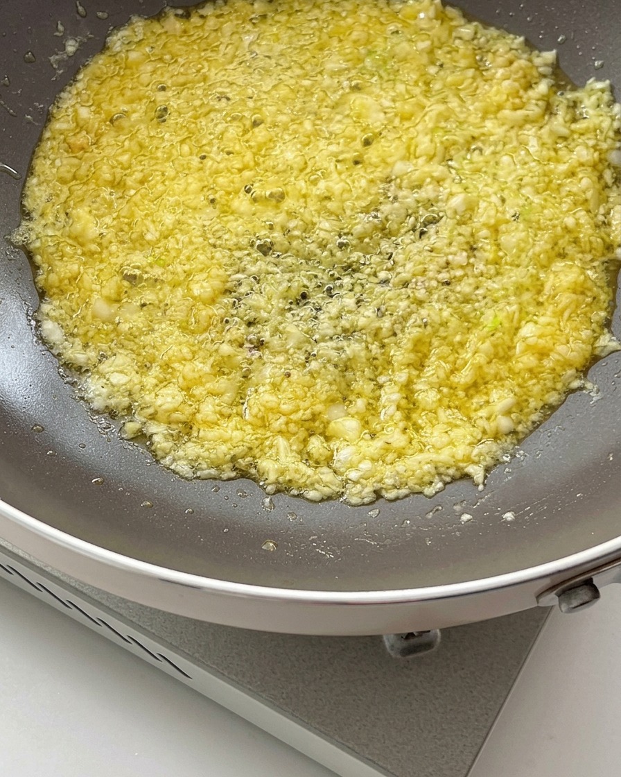 Sauce soja et sauce huître versées dans le mélange grésillant de beurre et dail à lintérieur dune poêle.