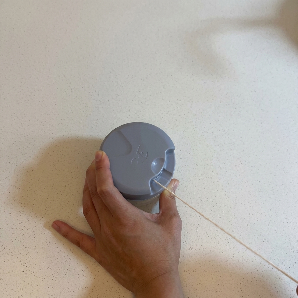 Mains utilisant un hachoir manuel à tirette sur un comptoir blanc pour hacher de lail.
