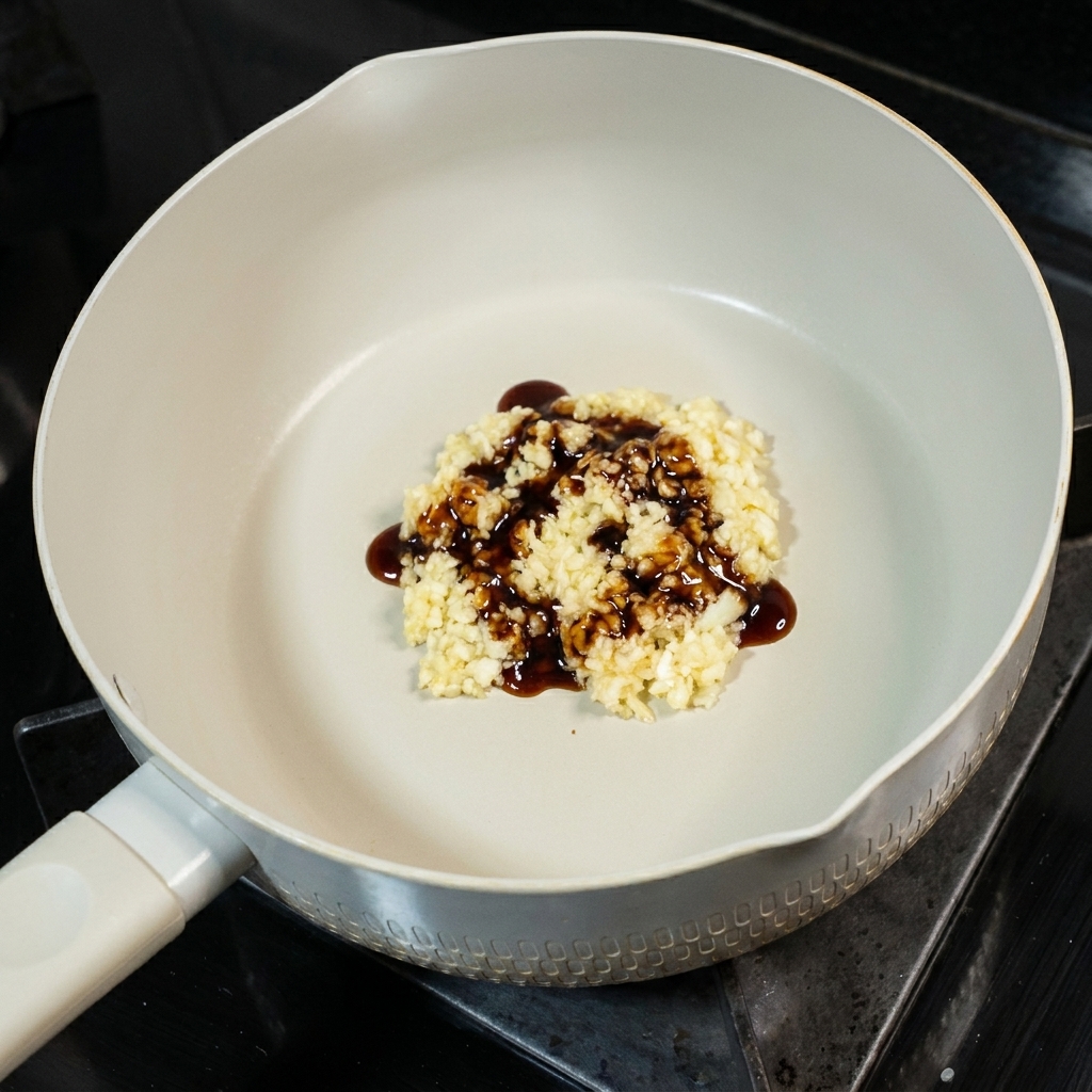 Une petite cuillère de sucre ajoutée au mélange dail et de sauce soja dans la poêle.