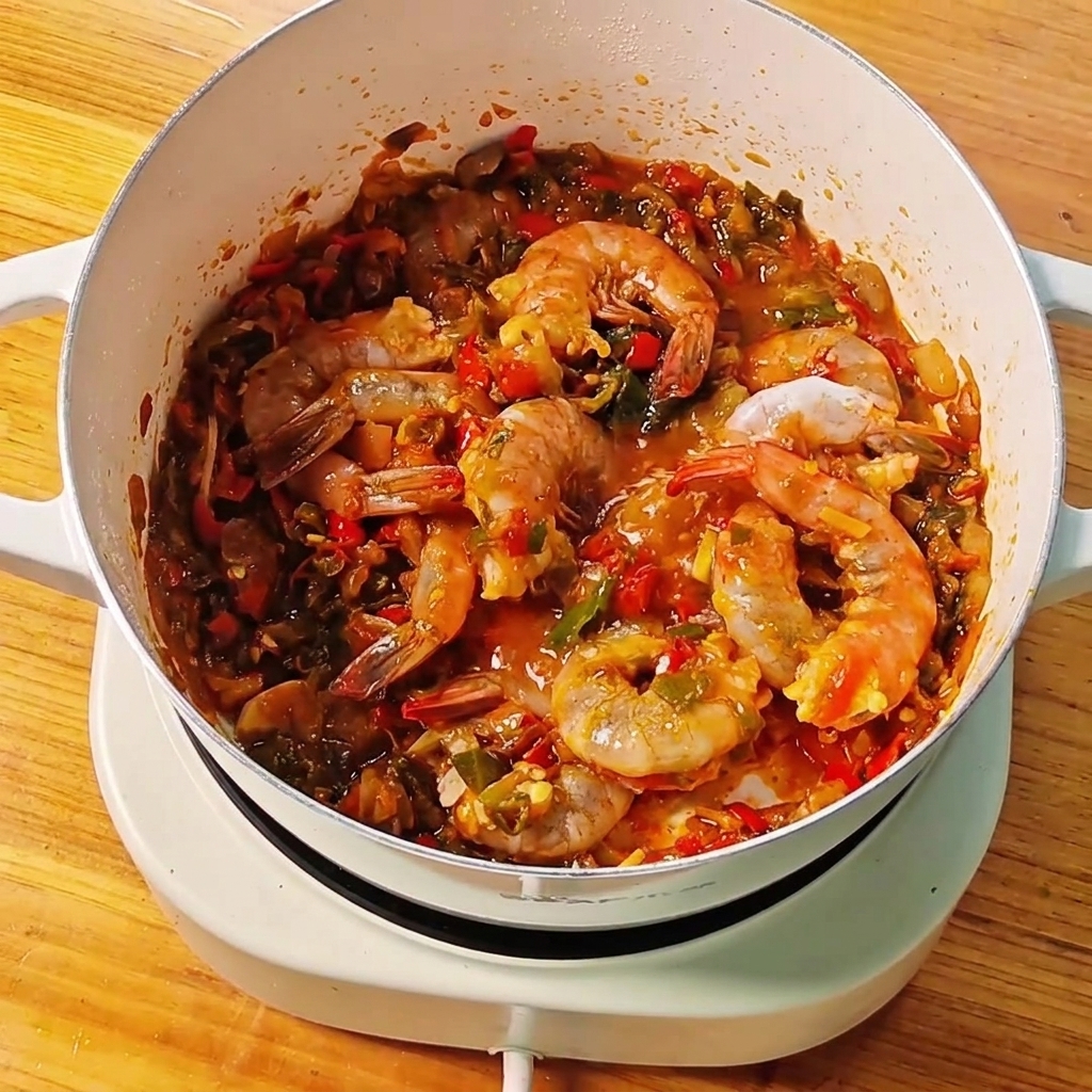 Eau claire versée dun petit bol dans une poêle contenant les crevettes et la sauce.