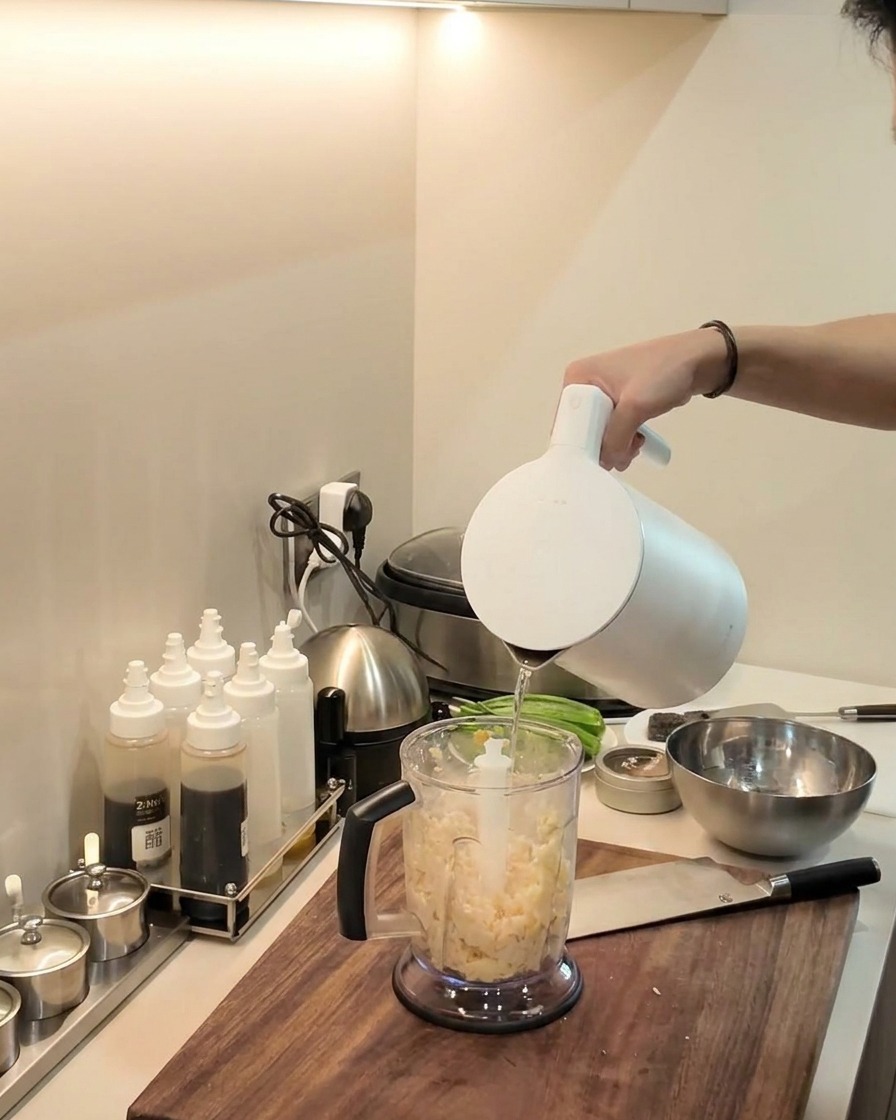 Un mixeur plongeant réduisant en purée le mélange de manioc et de plantain à lintérieur du pichet du mixeur.