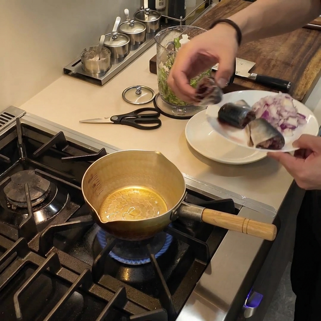 Une petite casserole dorée posée sur un brûleur à gaz avec de lhuile de cuisson frémissante à lintérieur.