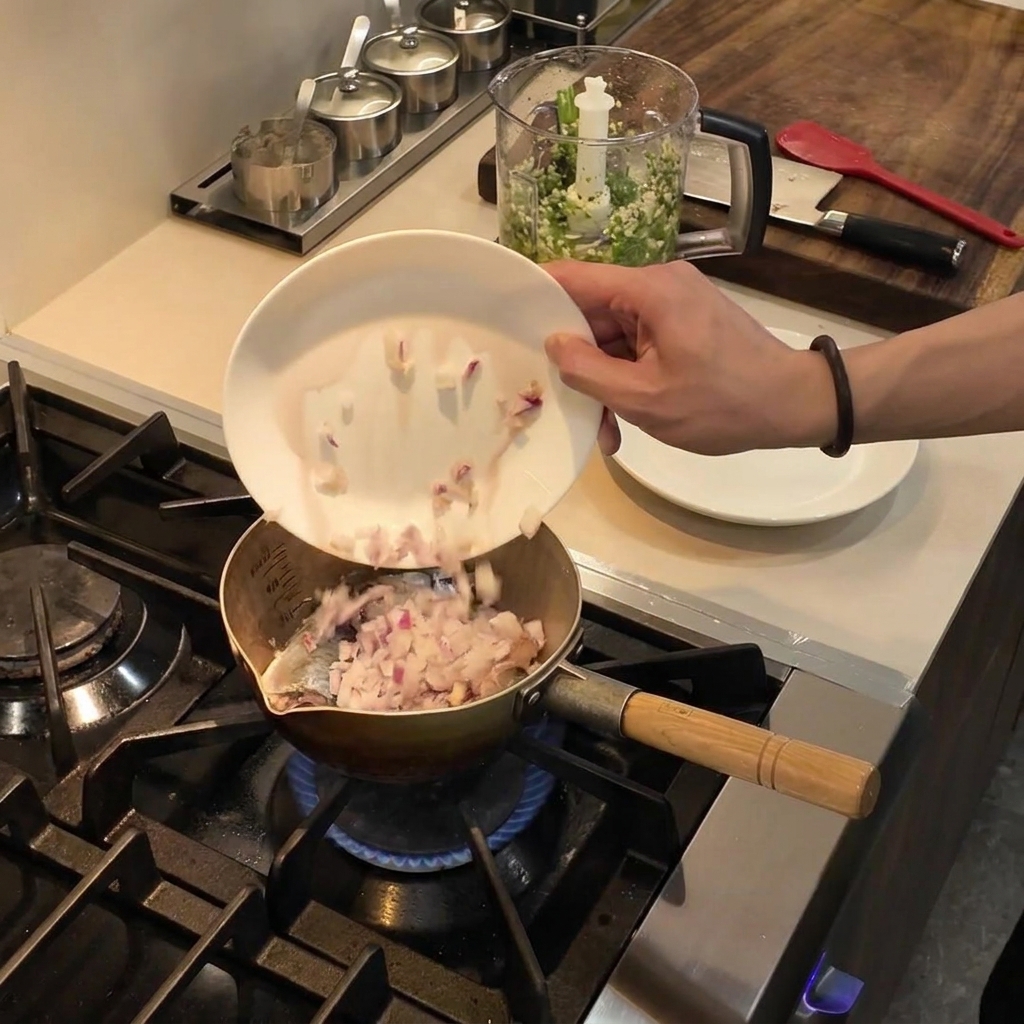 Des oignons rouges émincés glissant dune assiette blanche dans une casserole dhuile chaude sur le feu.