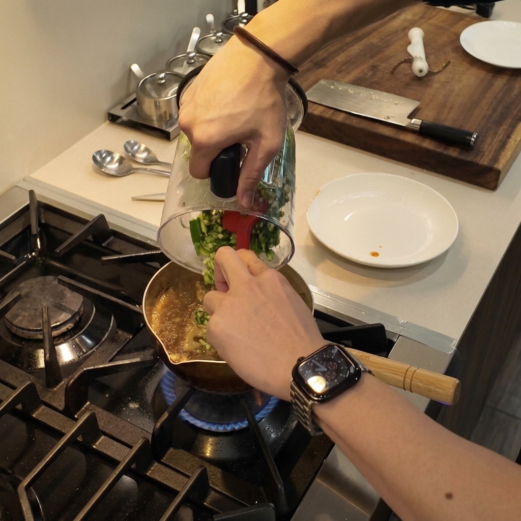 Du gombo vert haché raclé dun bol de mixeur dans une casserole de ragoût frémissant à laide dune spatule rouge.