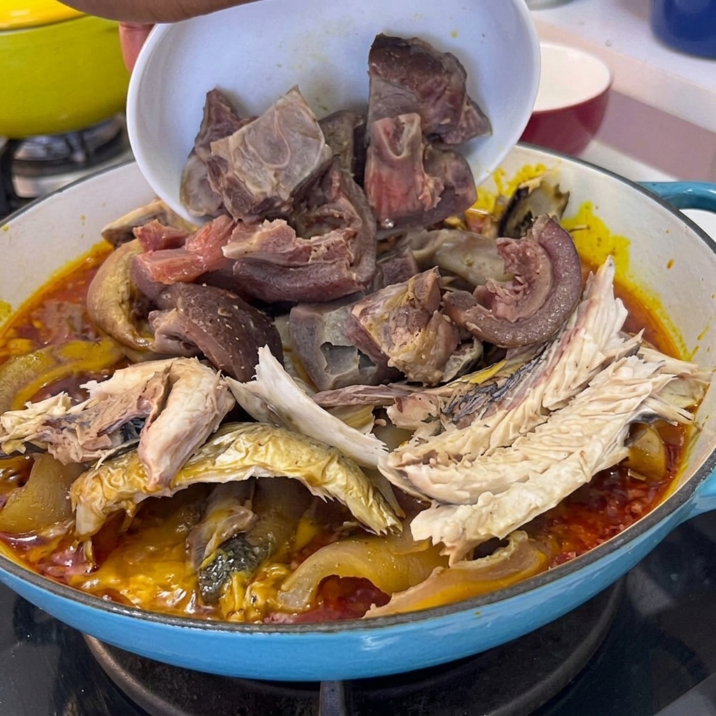 Des morceaux de viande de porc cuite versés dun bol dans la casserole contenant le poisson et la sauce.