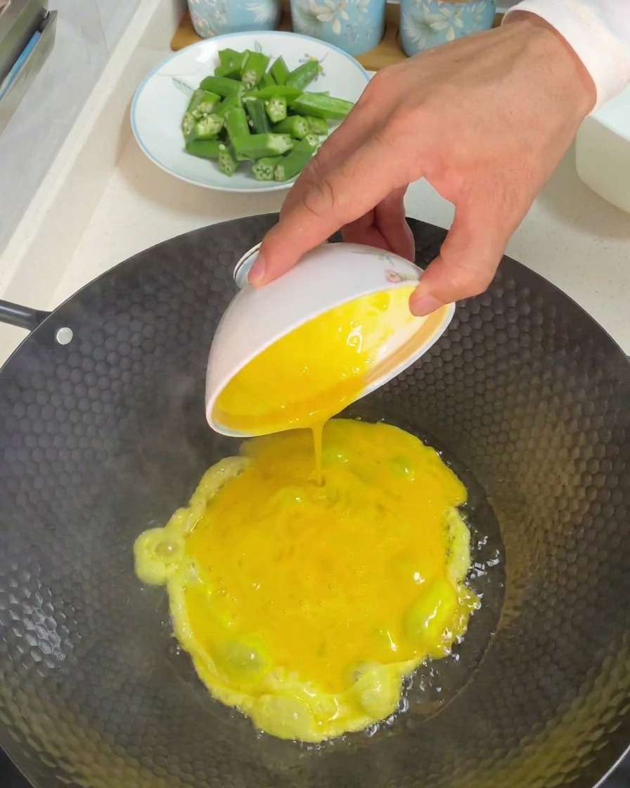 Verser un bol dœufs battus jaunes dans un wok chaud avec de lhuile.