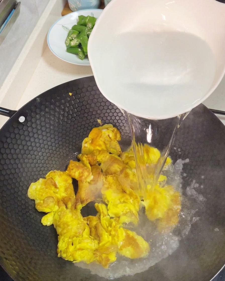 Verser de leau très chaude dun grand bol blanc sur des œufs brouillés pour créer une base de soupe.