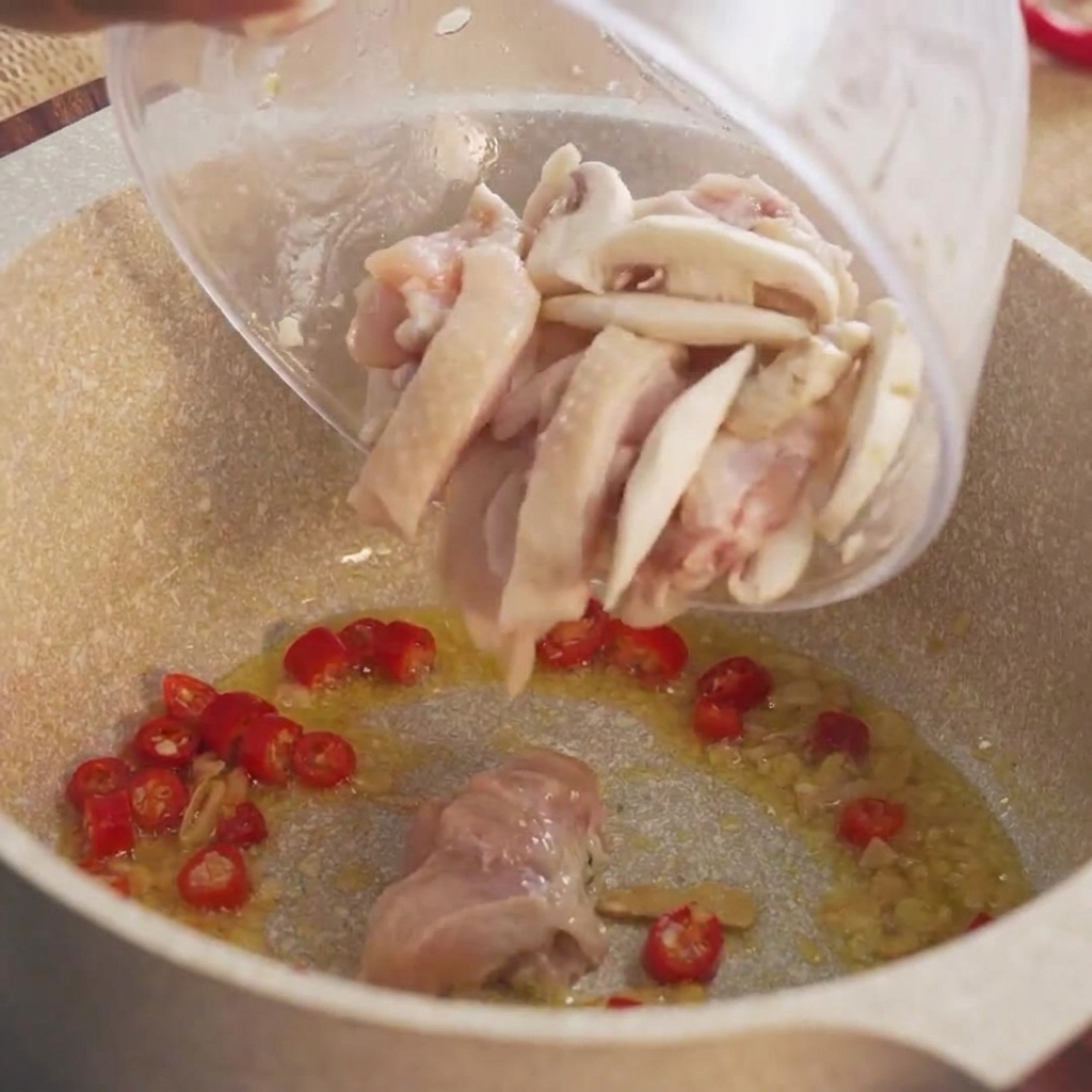 Des morceaux marinés de poulet cru versés dun bol dans la casserole chaude.