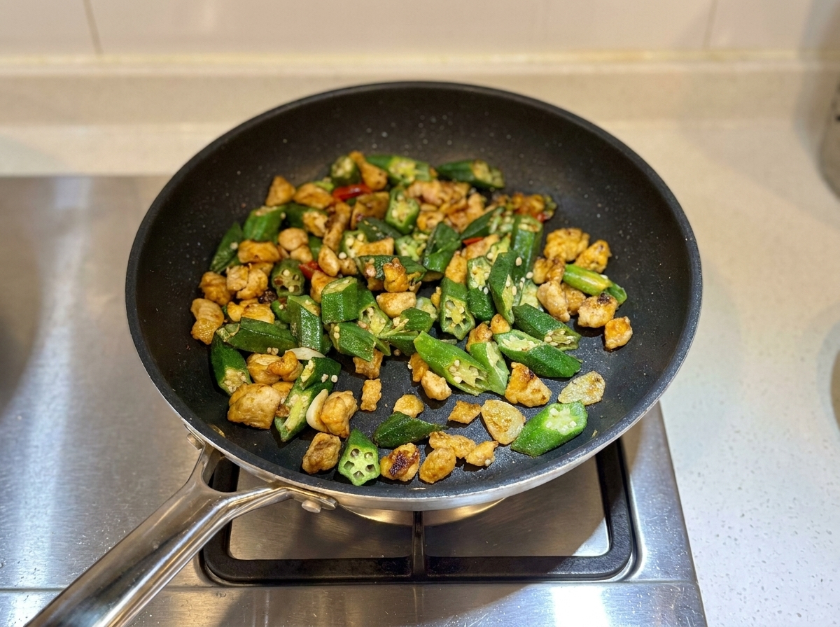 Le sauté de poulet et de gombos terminé dans la poêle, légèrement caramélisé et prêt à être servi.