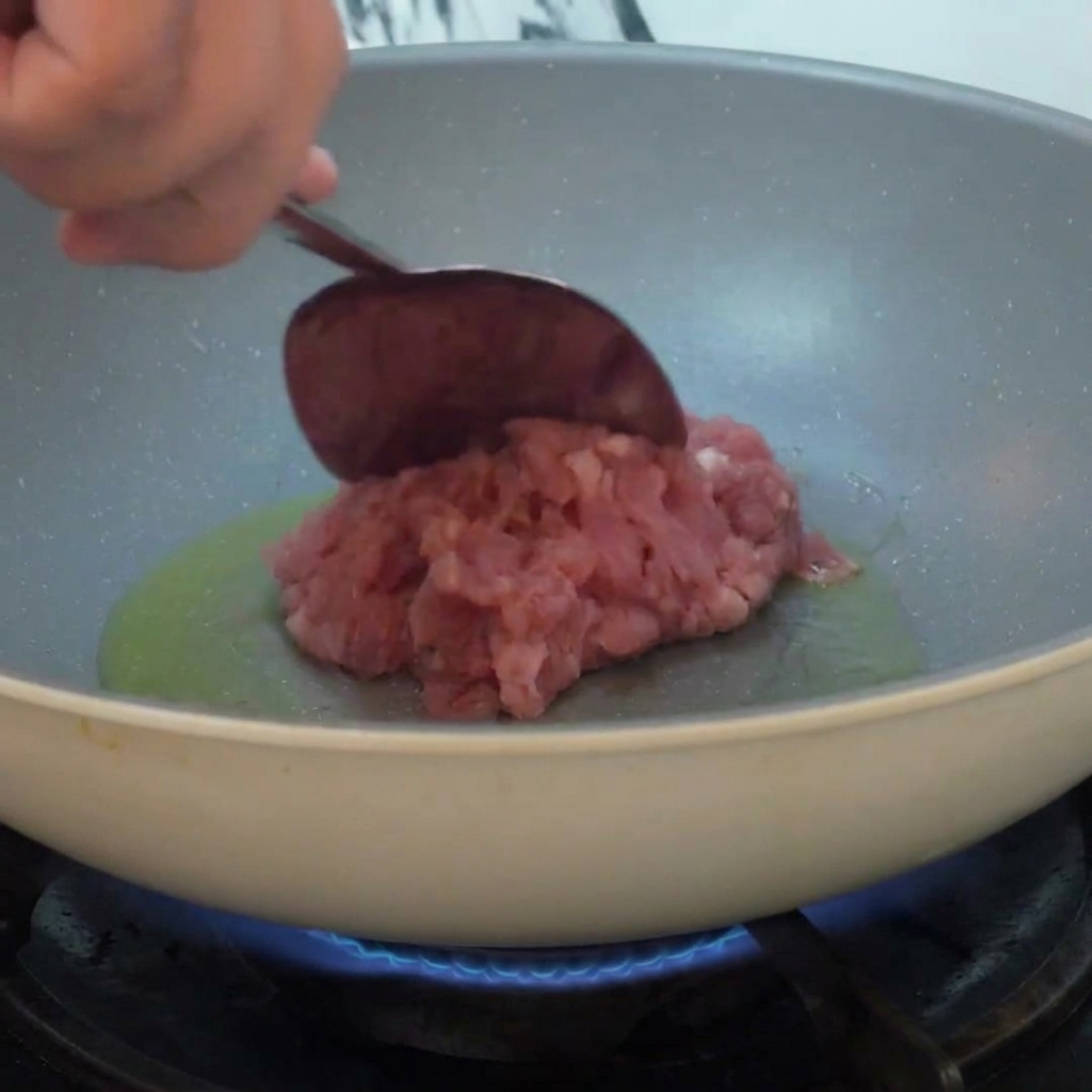 Viande hachée ajoutée dans une poêle avec de lhuile chaude et sautée sur le feu.