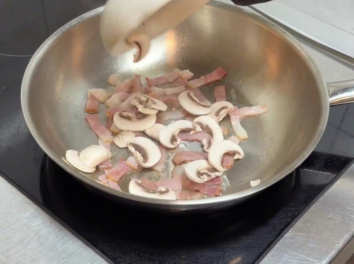 Champignons émincés ajoutés dans la poêle contenant les lardons dorés.