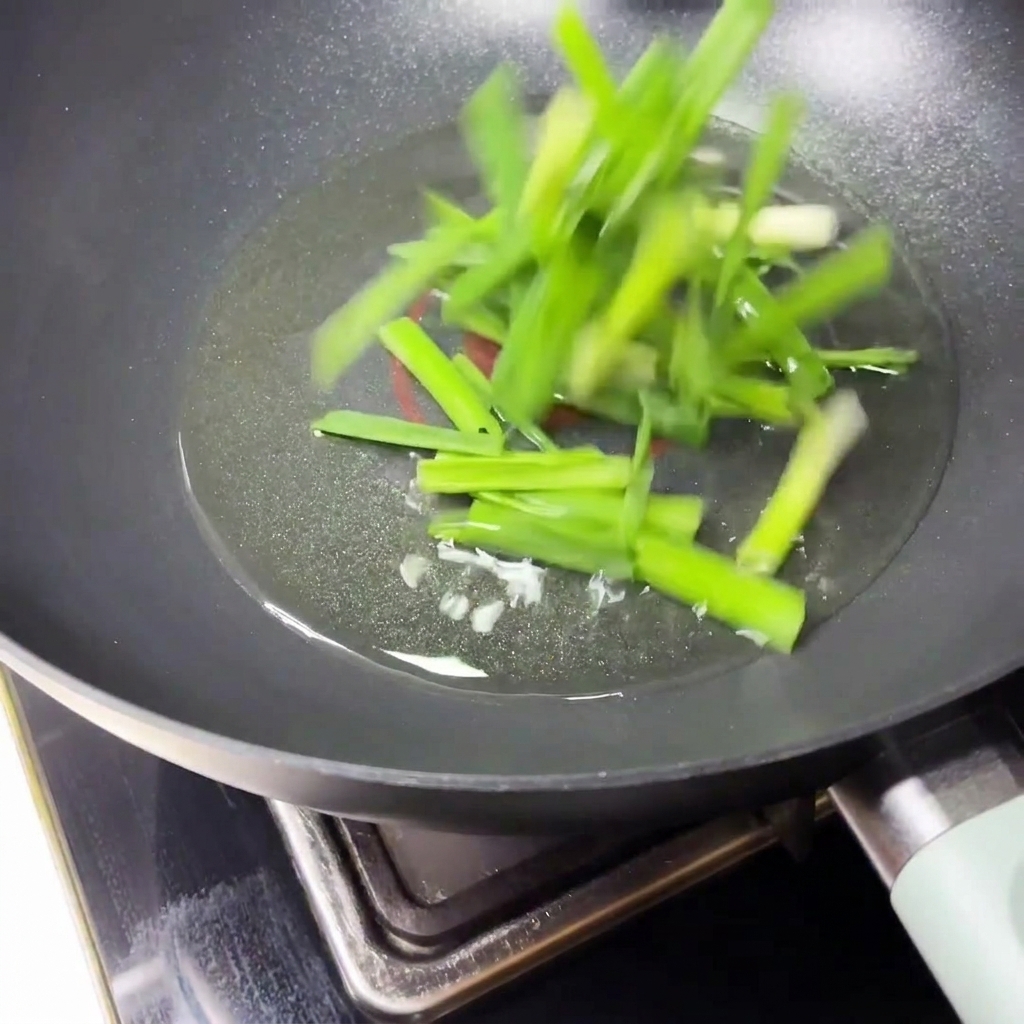 Cébettes émincées sautées dans lhuile chaude dans une poêle noire.