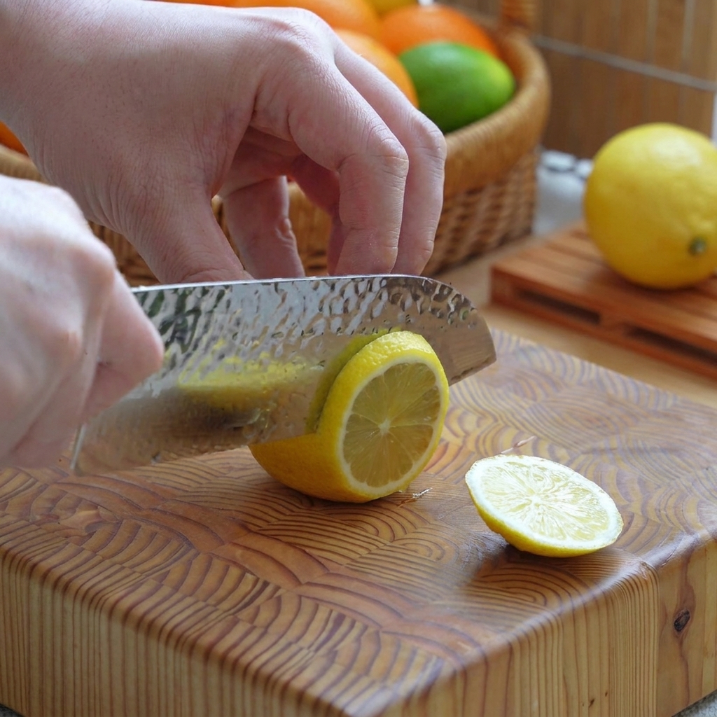 Un citron jaune coupé en rondelles nettes sur une planche à découper en bois à laide dun couteau.