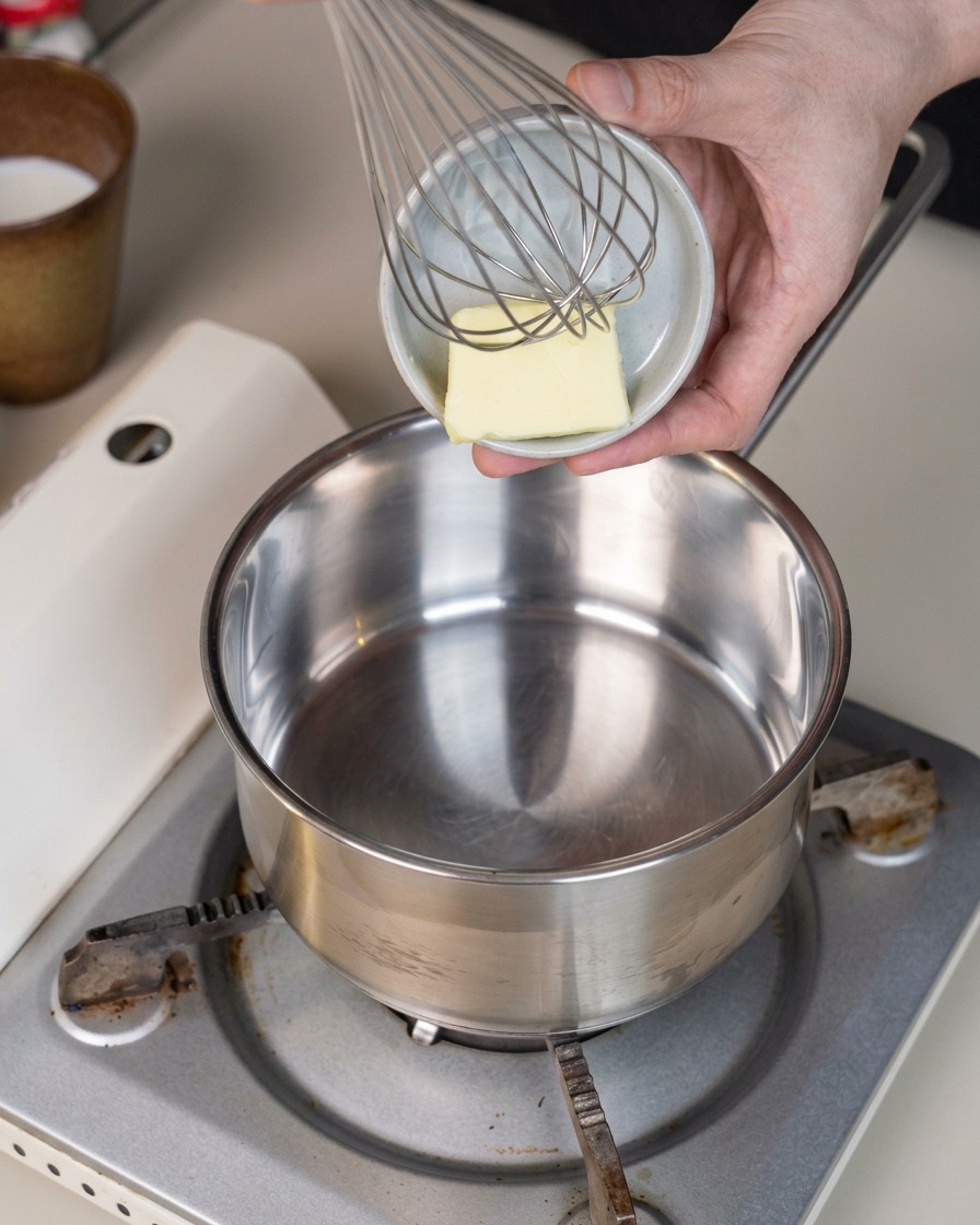 Un petit morceau de beurre placé au fond dune casserole en métal propre posée sur un réchaud.