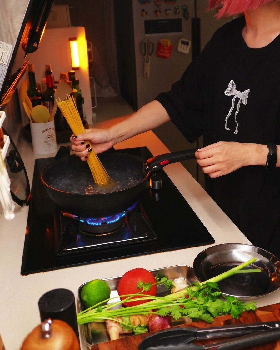 Spaghettis secs plongés dans une casserole deau bouillante sur une cuisinière.