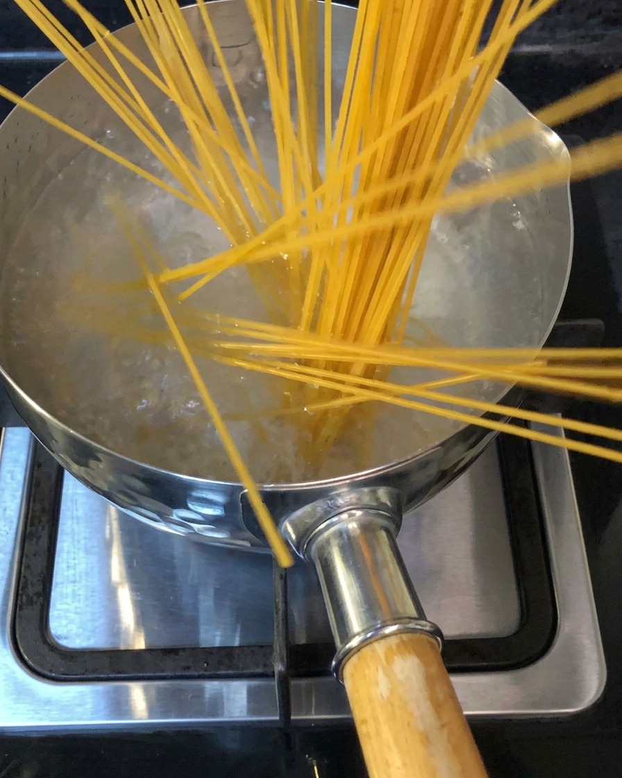 Des nouilles de spaghetti plongées dans une casserole deau bouillante salée sur une cuisinière.