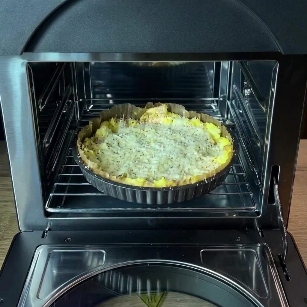Le plat de cuisson avec la croûte de pommes de terre assaisonnée placé sur la grille du four à lintérieur du four.