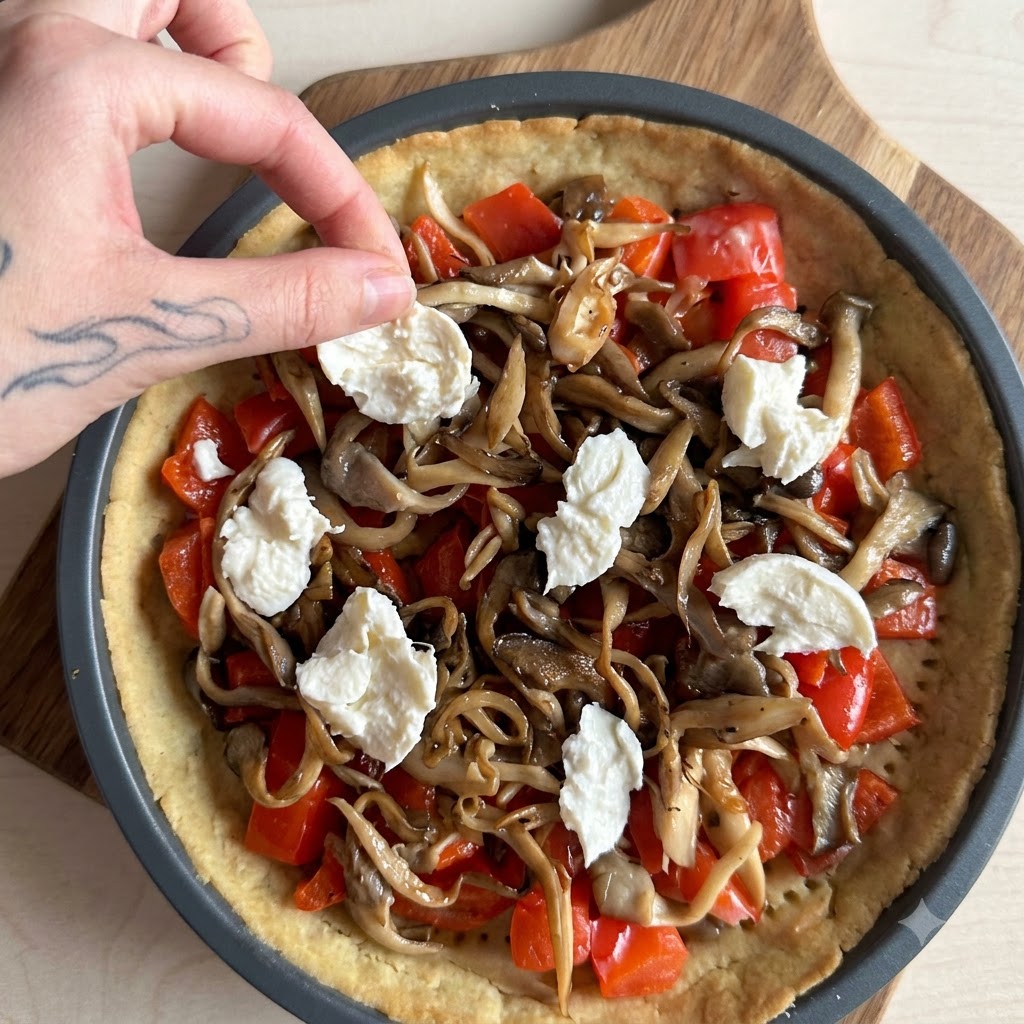 De la crème versée sur une tarte garnie de saumon, de champignons et de mozzarella.