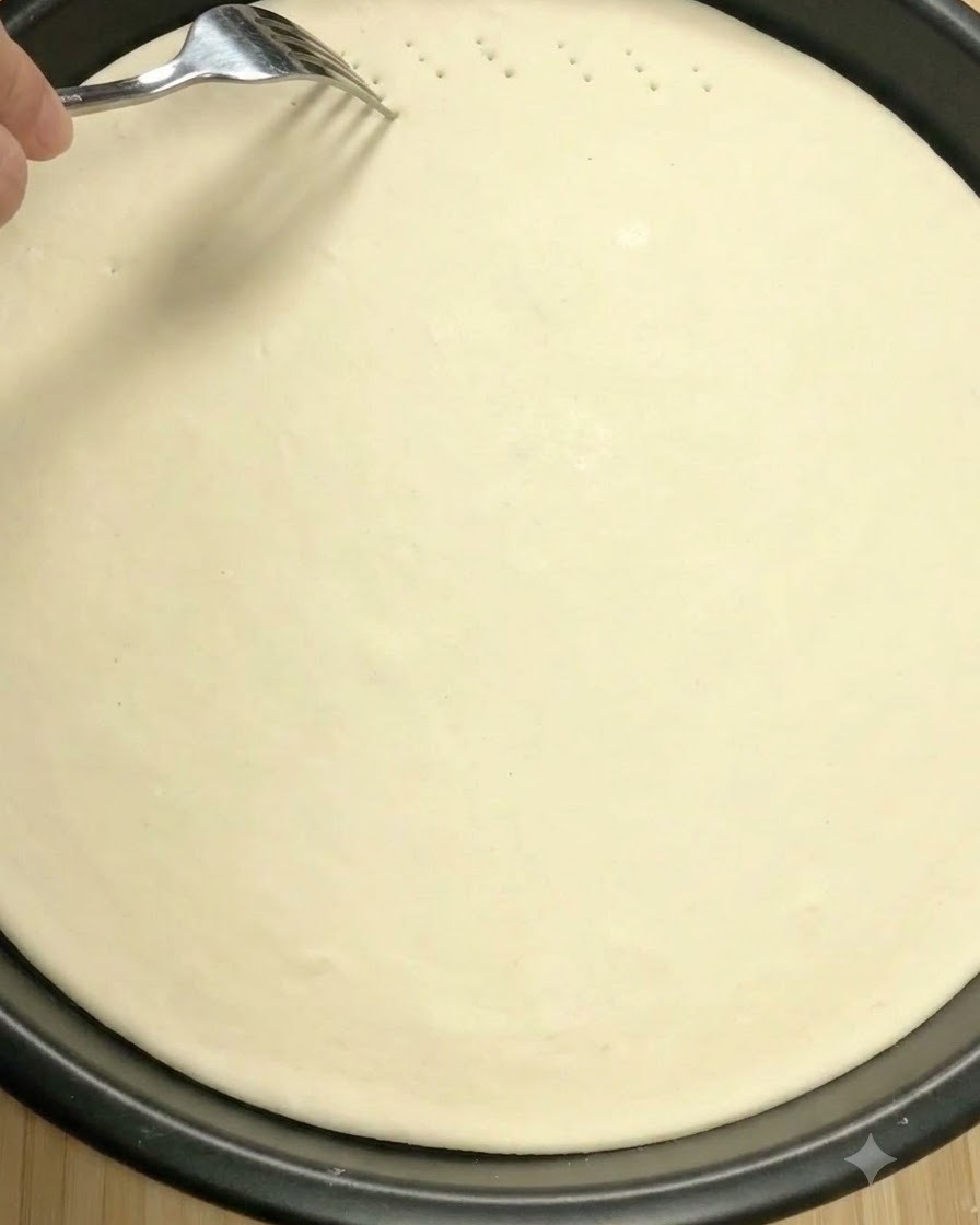Une fourchette en métal faisant de petits trous de ventilation à la surface de la pâte à pizza crue.