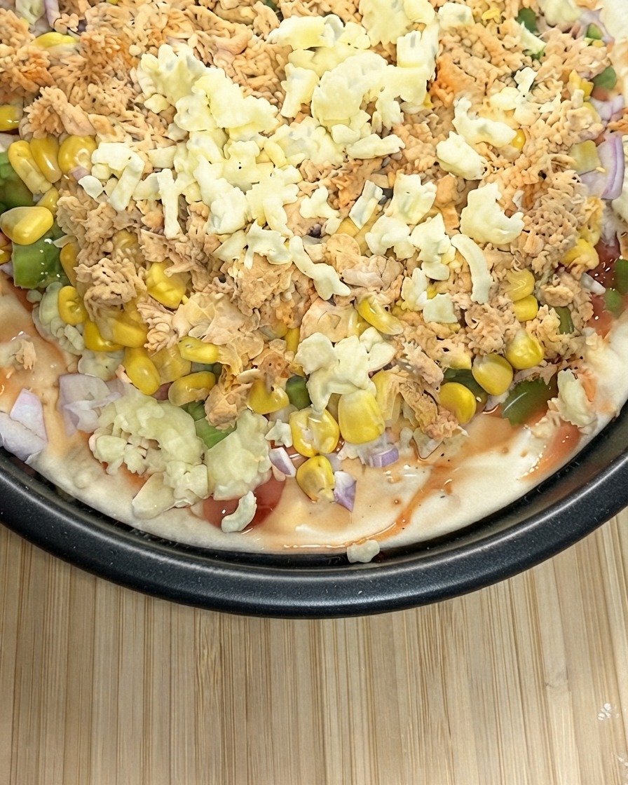 Vue rapprochée dune pizza préparée recouverte généreusement dune épaisse couche de mozzarella râpée.
