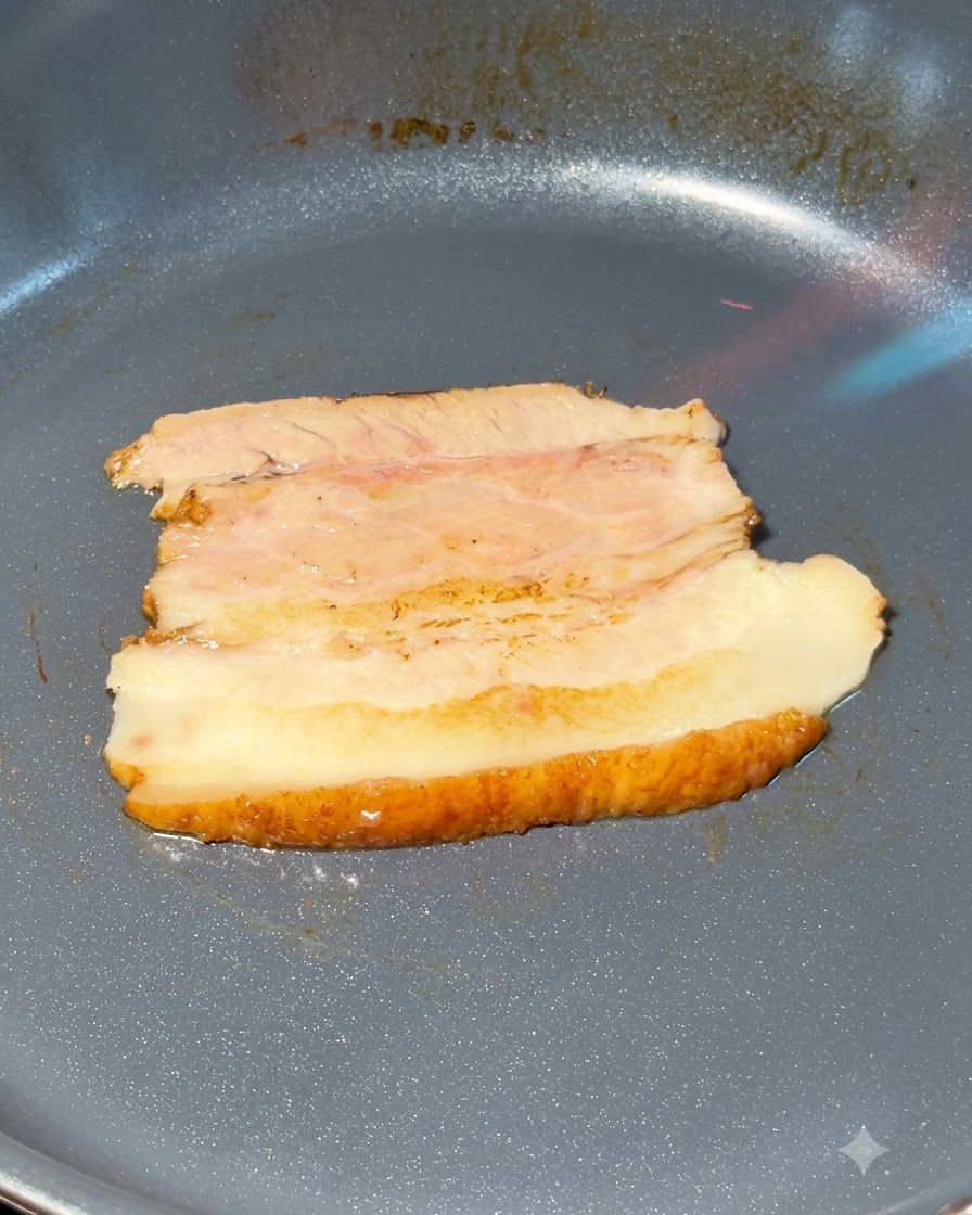 Tranches de poitrine de porc chashu en train dêtre flambées dans une poêle.