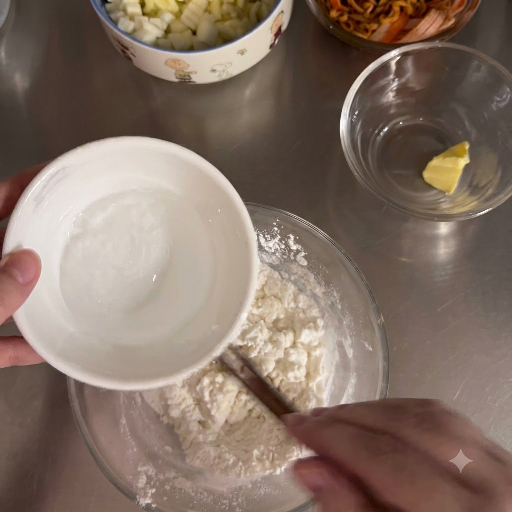 Eau chaude versée dun petit bol blanc dans un bol en verre rempli du mélange de farine.