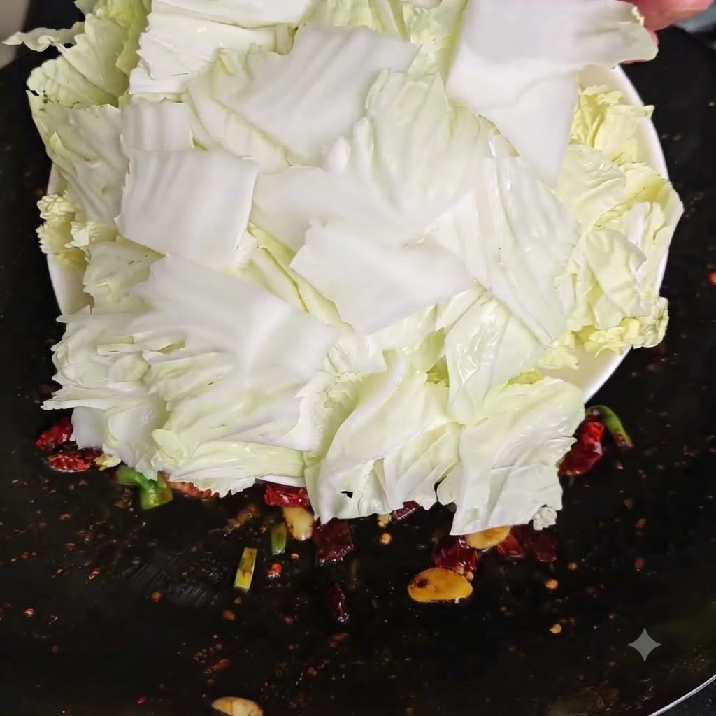 Des morceaux de chou chinois cru fraîchement hachés basculés depuis une assiette blanche dans un wok chaud.