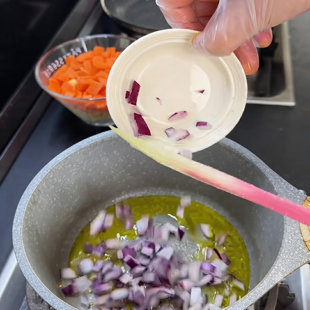 Morceaux doignon rouge versés dun petit bol blanc dans une casserole dhuile chaude.