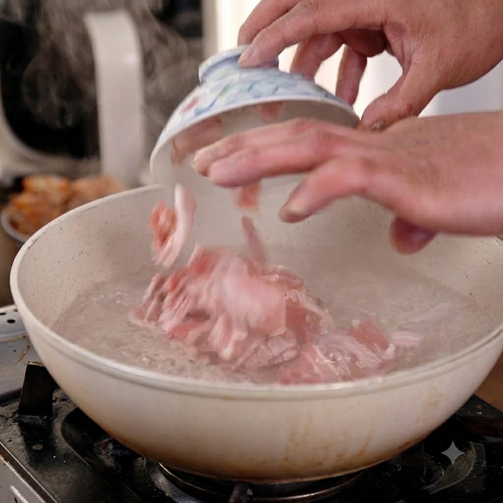 Des mains plongeant des tranches de poitrine de porc crue dun petit bol en céramique dans une casserole deau bouillante.