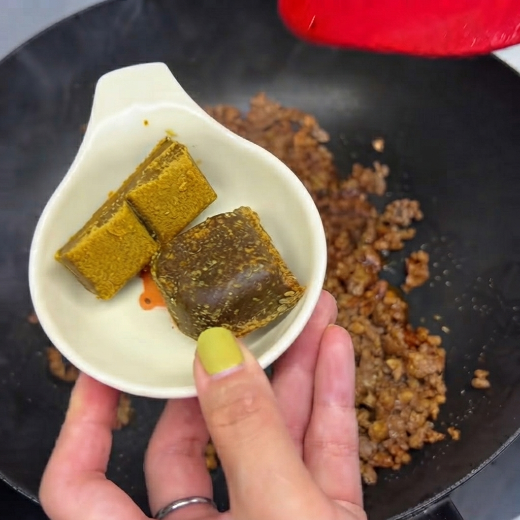 Deux blocs de curry tenus dans un petit plat blanc prêts à être jetés dans la poêle avec la viande hachée.