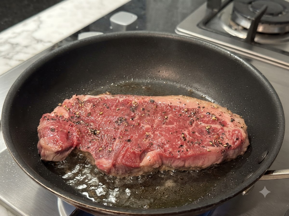 Un steak qui frit dans une poêle chaude, montrant une croûte dorée qui se forme à la surface.