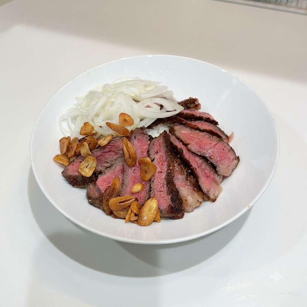 Un bol blanc contenant du steak tranché, des oignons tranchés et une dispersion de chips dail croustillantes dorées sur le riz.