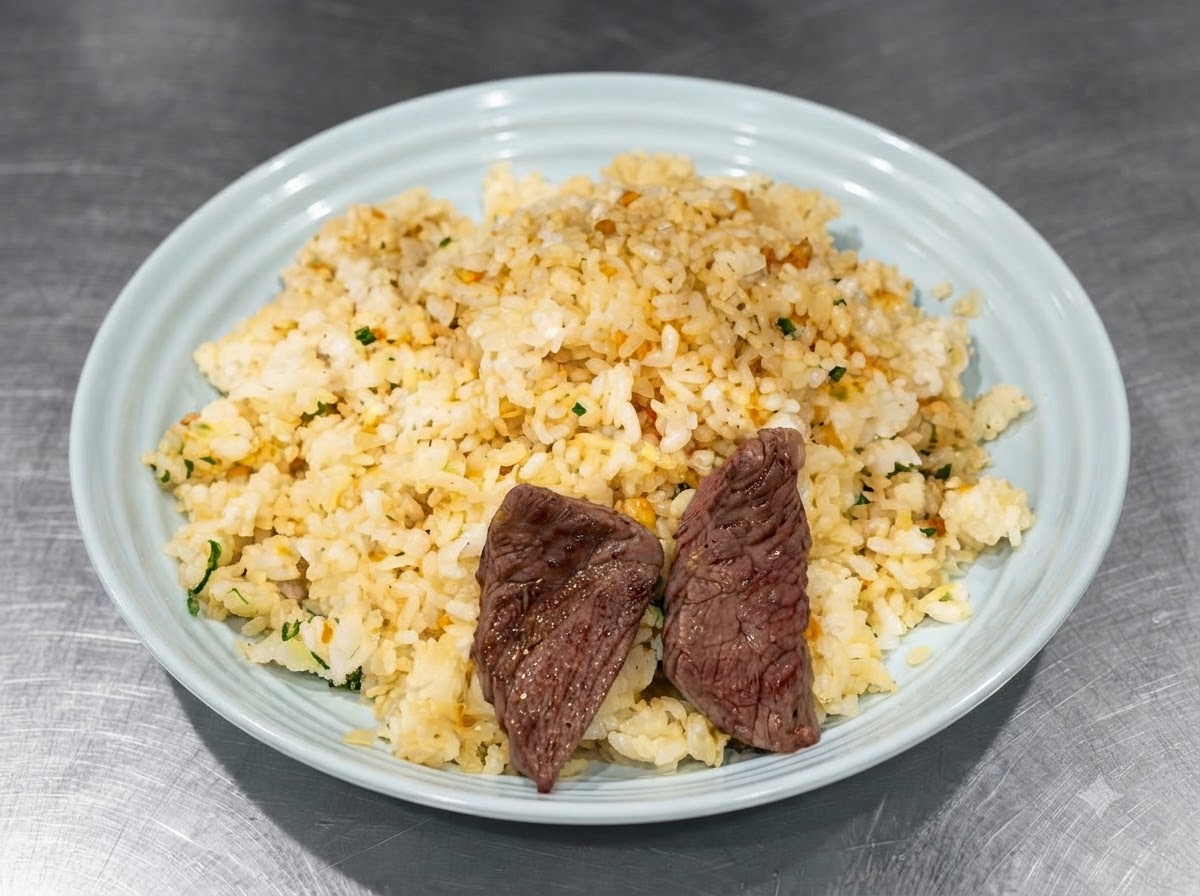 Morceaux de steak saisis disposés sur le riz assaisonné dans une assiette bleue à laide de pinces.