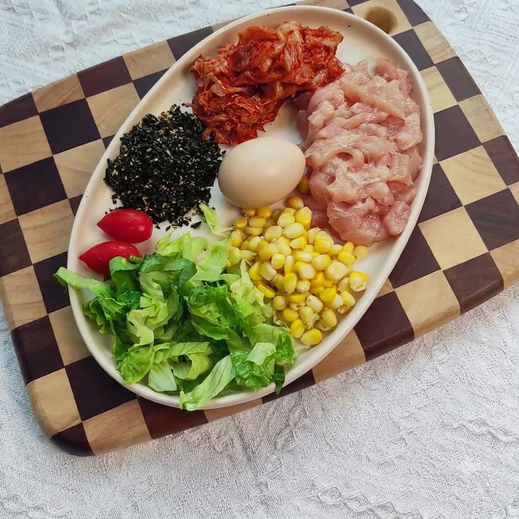 Blancs de poulet émincés dans un bol mélangés avec des aromates, du gingembre et de lail.