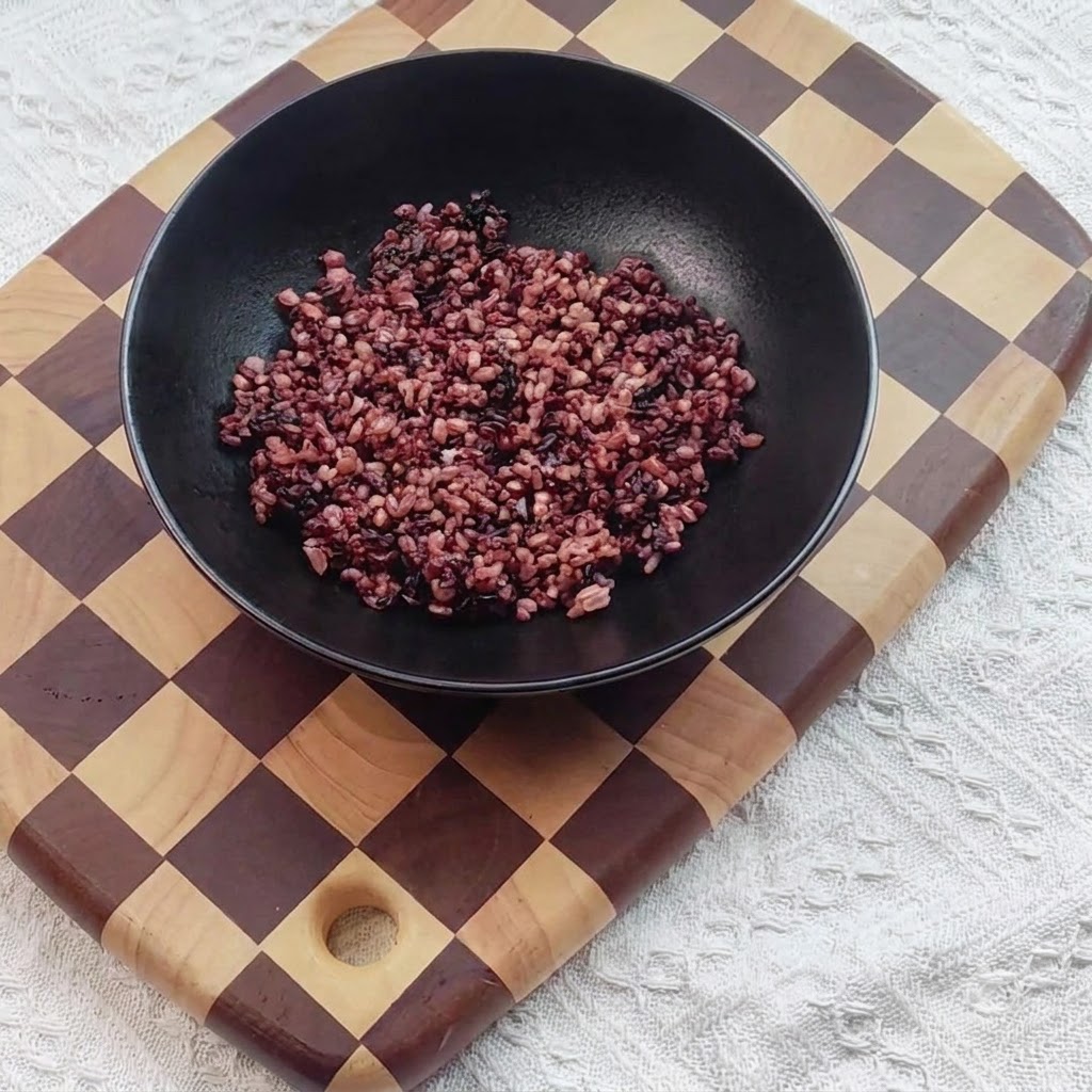 Riz noir cuit placé à lintérieur dun bol de service noir.