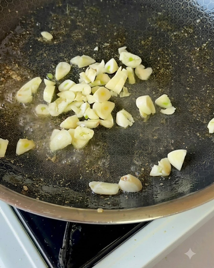 Des tranches dail frais frisant doucement dans lhuile de cuisson à lintérieur dune poêle antiadhésive.