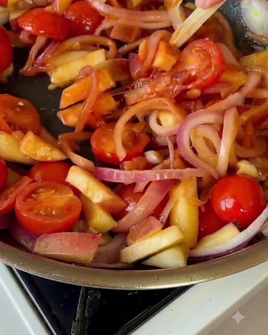 Du chou chinois mélangé dans la poêle avec les tomates et les oignons.