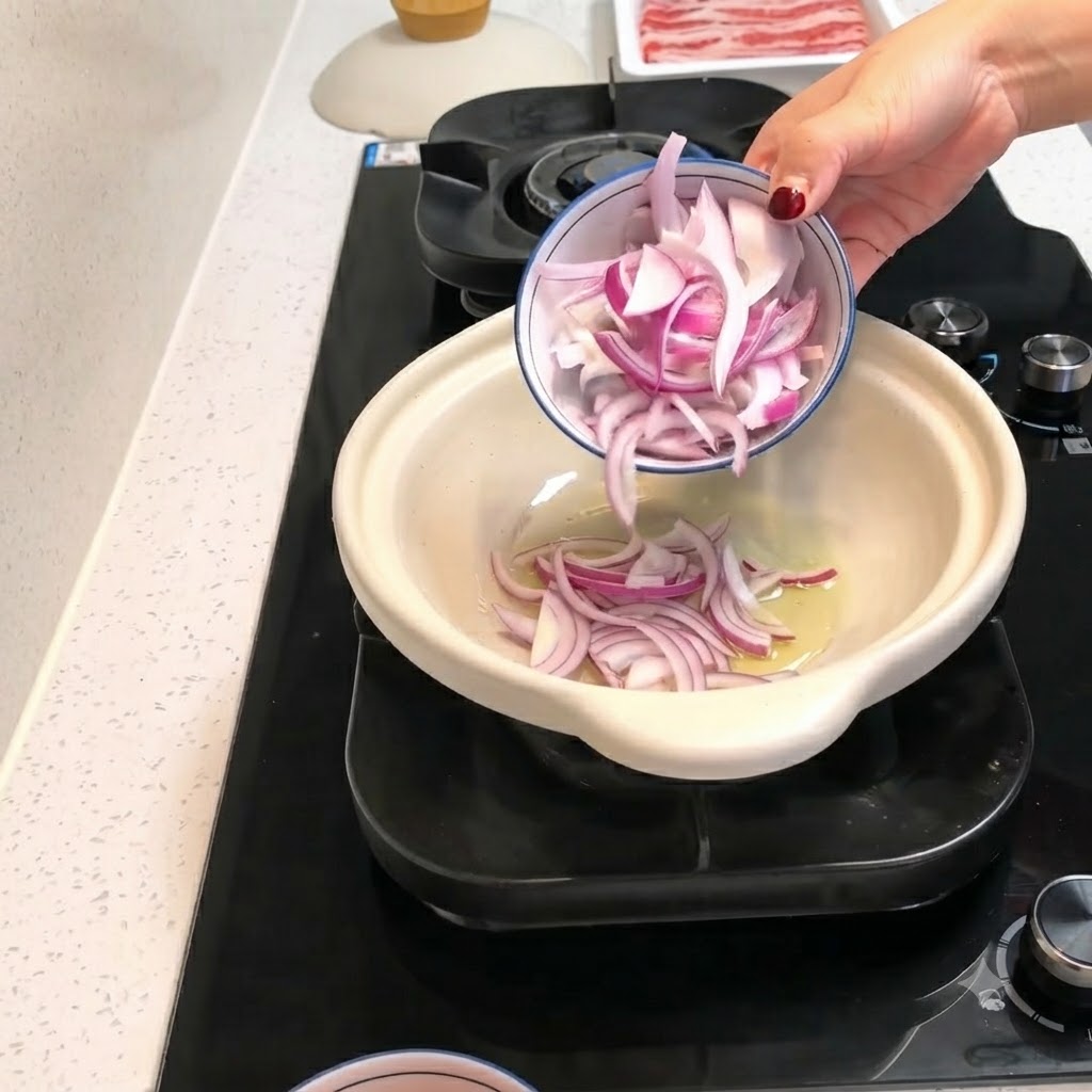 Tranches doignon rouge et morceaux de tomate pelée versés dun petit bol dans une cocotte chaude avec de lhuile.