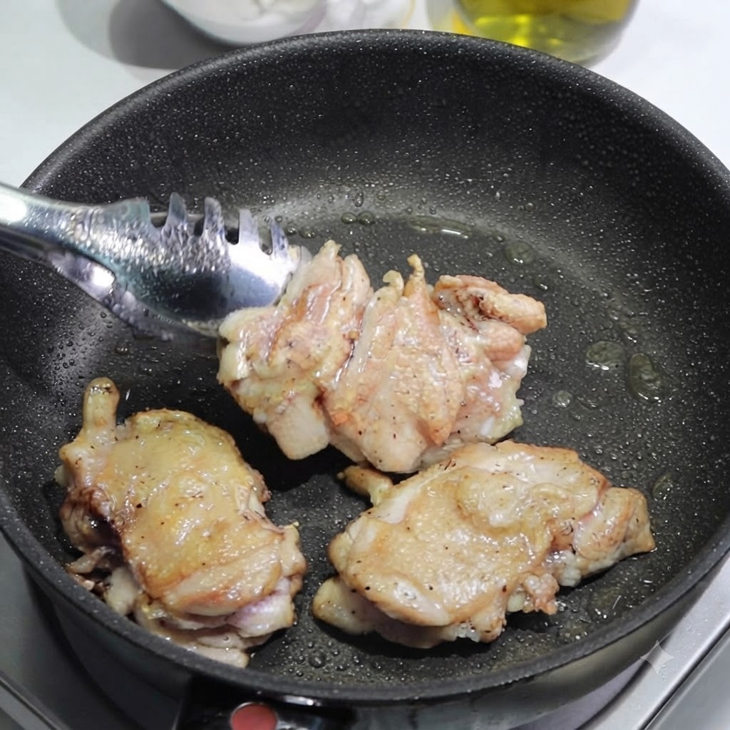 Pinces plaçant des hauts de cuisse de poulet dorés hors dune poêle sur une planche à découper pour être tranchés.