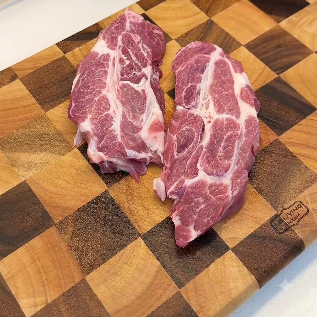 Morceaux déchine de porc crus en train dêtre aplatis avec un maillet à viande en métal sur une planche à découper en bois.