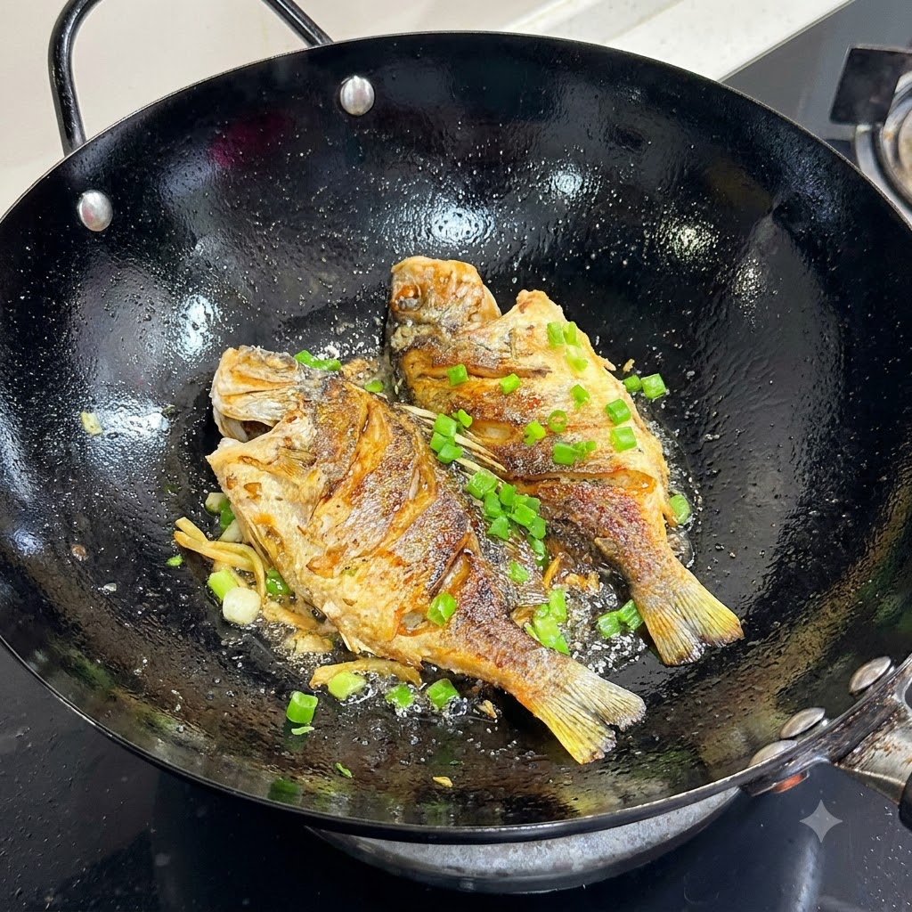Des oignons verts fraîchement hachés saupoudrés sur le dessus du poisson doré poêlé dans un wok noir.