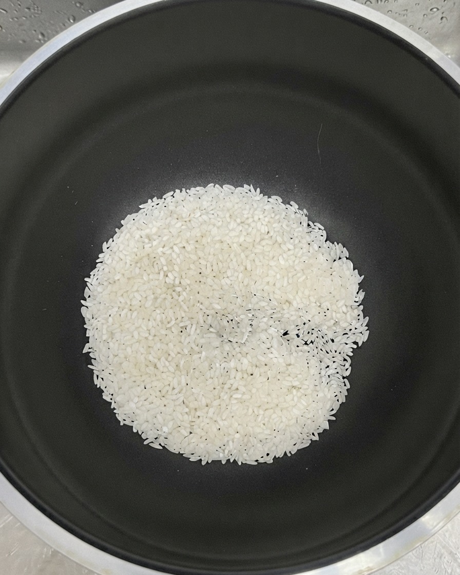 Riz blanc rassemblé au fond dun pot noir avec de leau ajoutée pour le rinçage.