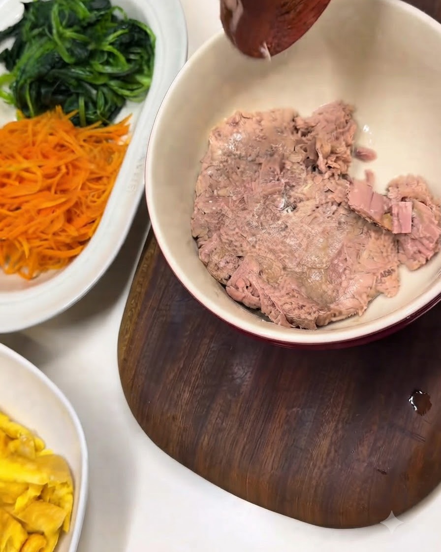 Un bol de thon en conserve émietté à côté dun plat blanc avec des épinards et des carottes préparés.