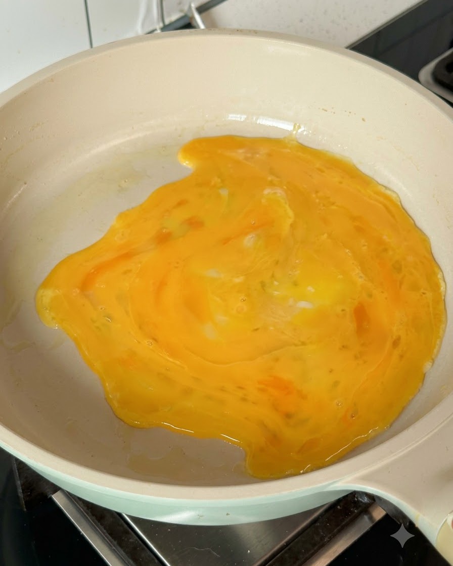 Des œufs battus sétalant dans la poêle chaude pour former une crêpe aux œufs.