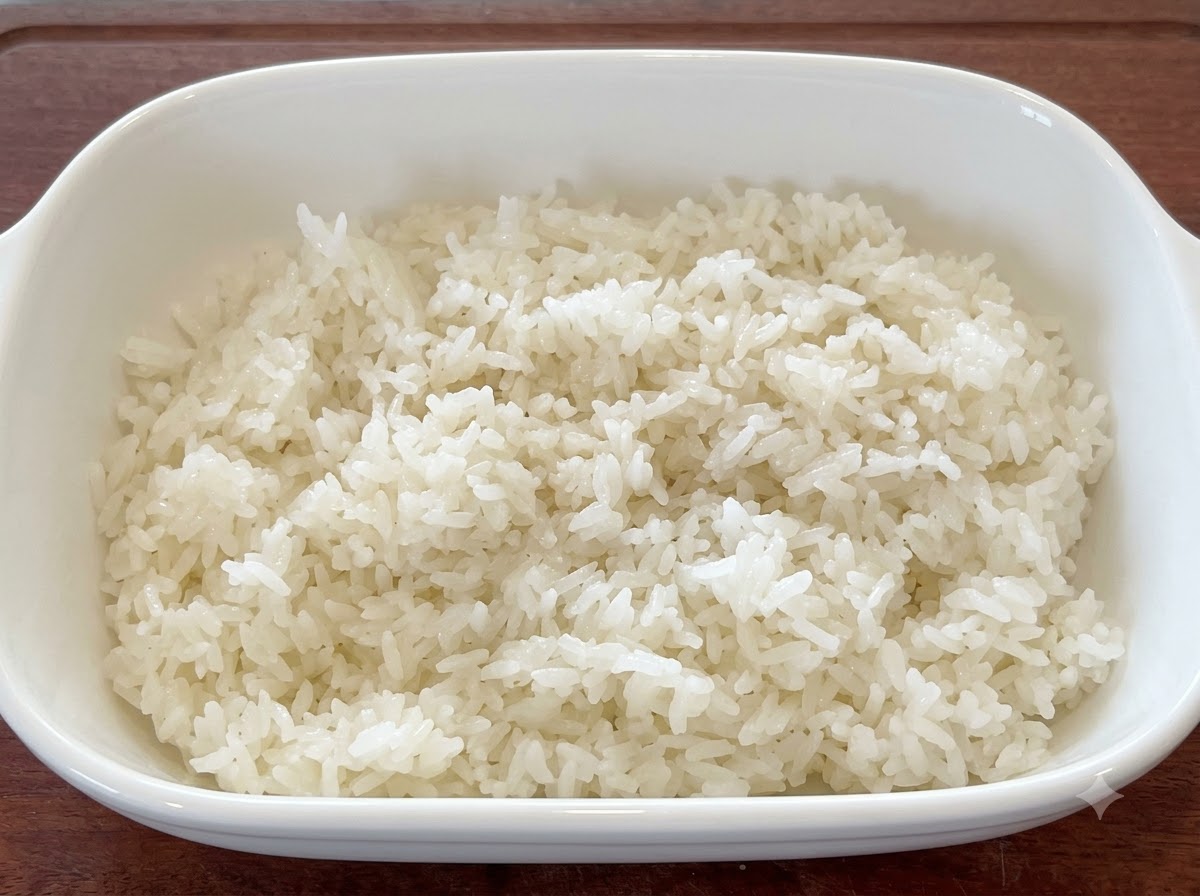 Riz blanc frais mélangé avec des graines de sésame et de lhuile dans un plat de service blanc.