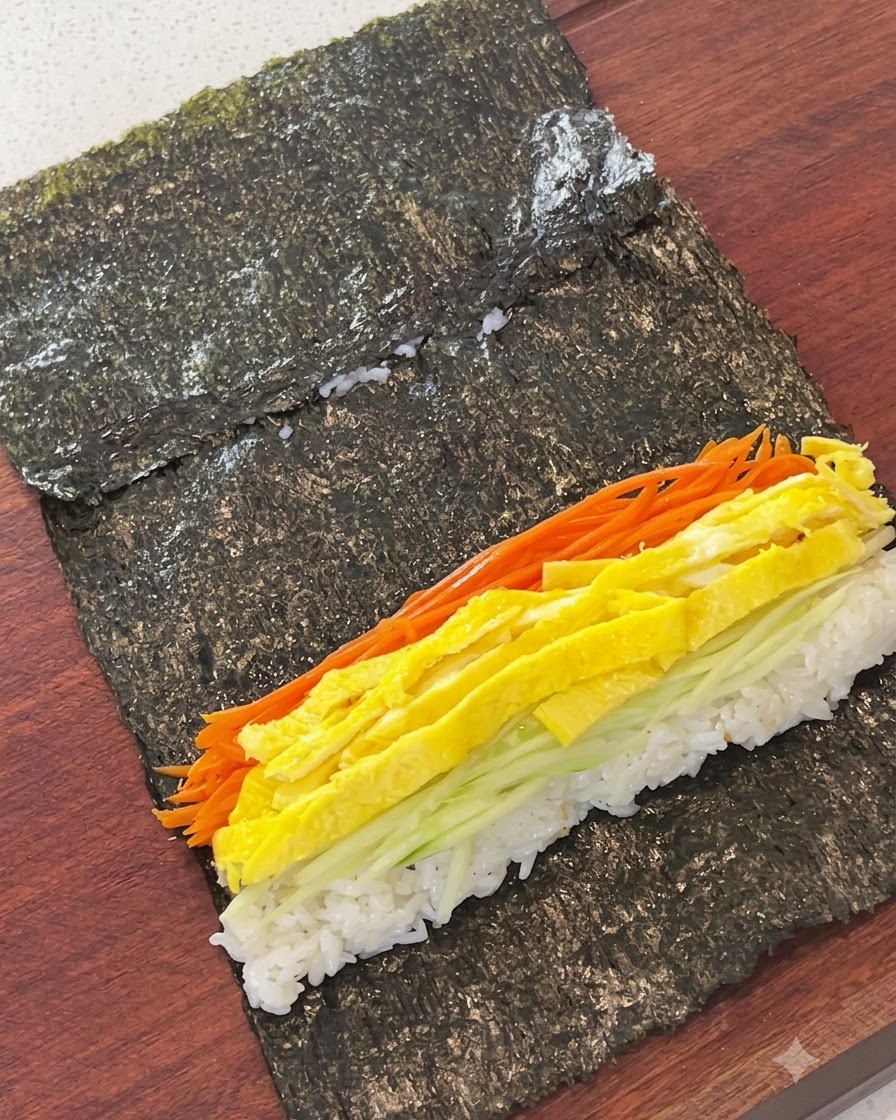 Carottes râpées, lamelles dœuf, concombre et gâteau de poisson disposés sur le riz dune feuille dalgue.