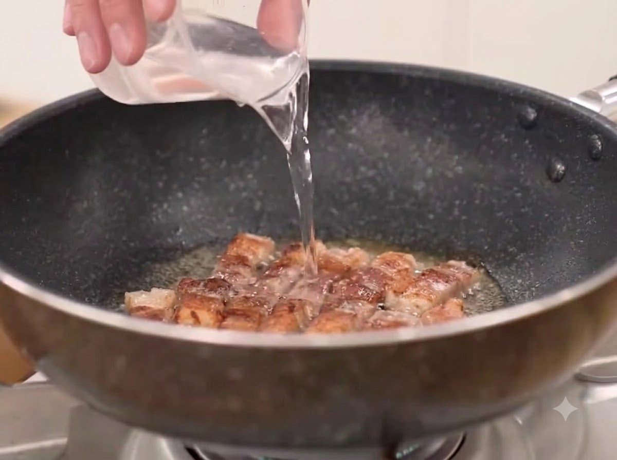 Eau, piment en poudre grossier et kimchi ajoutés dans la poêle avec la poitrine de porc frite.