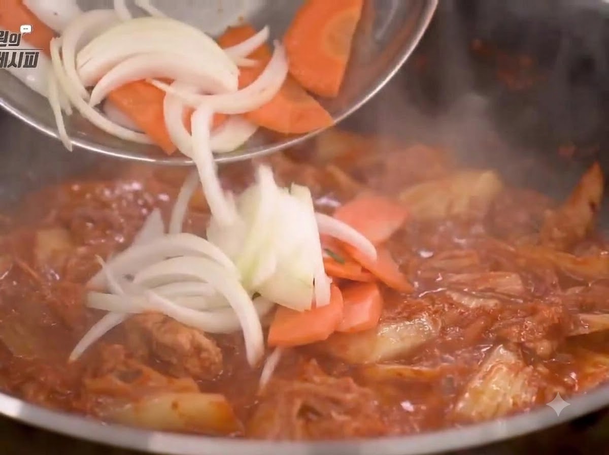 Oignons et carottes coupés ajoutés dans la poêle et sautés avec le mélange de kimchi.